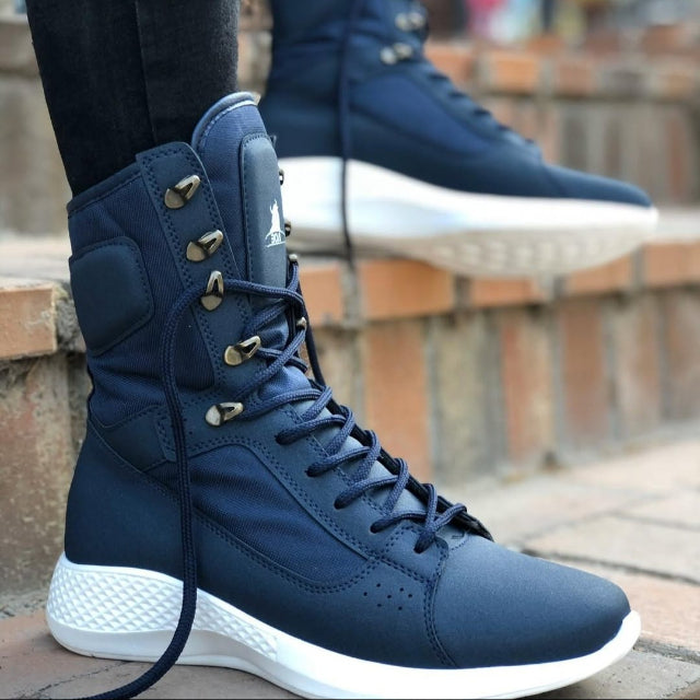 Navy high-top sneakers with white soles worn by a person on a stone step.