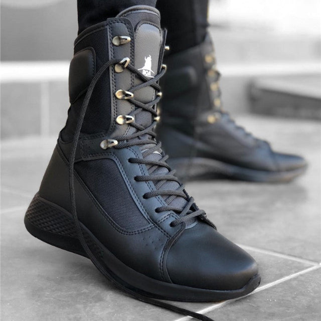 Black high-top sneakers with gold accents on a concrete floor.