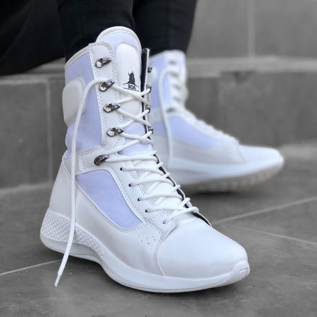 White high-top sneakers with a subtle purple accent on a gray pavement background